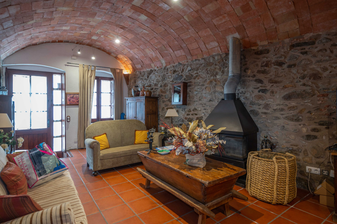 Vaulted ceiling in rustic styled living room with iron fireplace in a village house in Calonge.